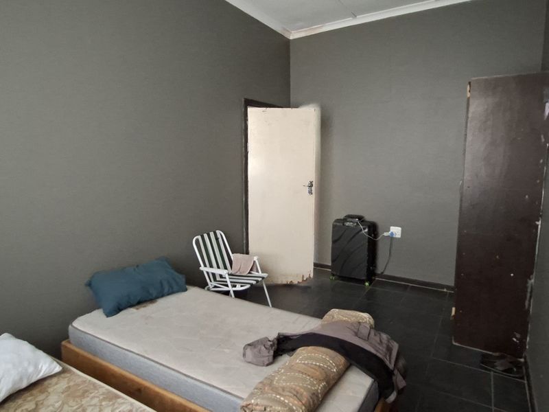 A bedroom featuring dark grey walls, tiled flooring, and a built-in cupboard, offering a blank canvas for potential interior design updates.