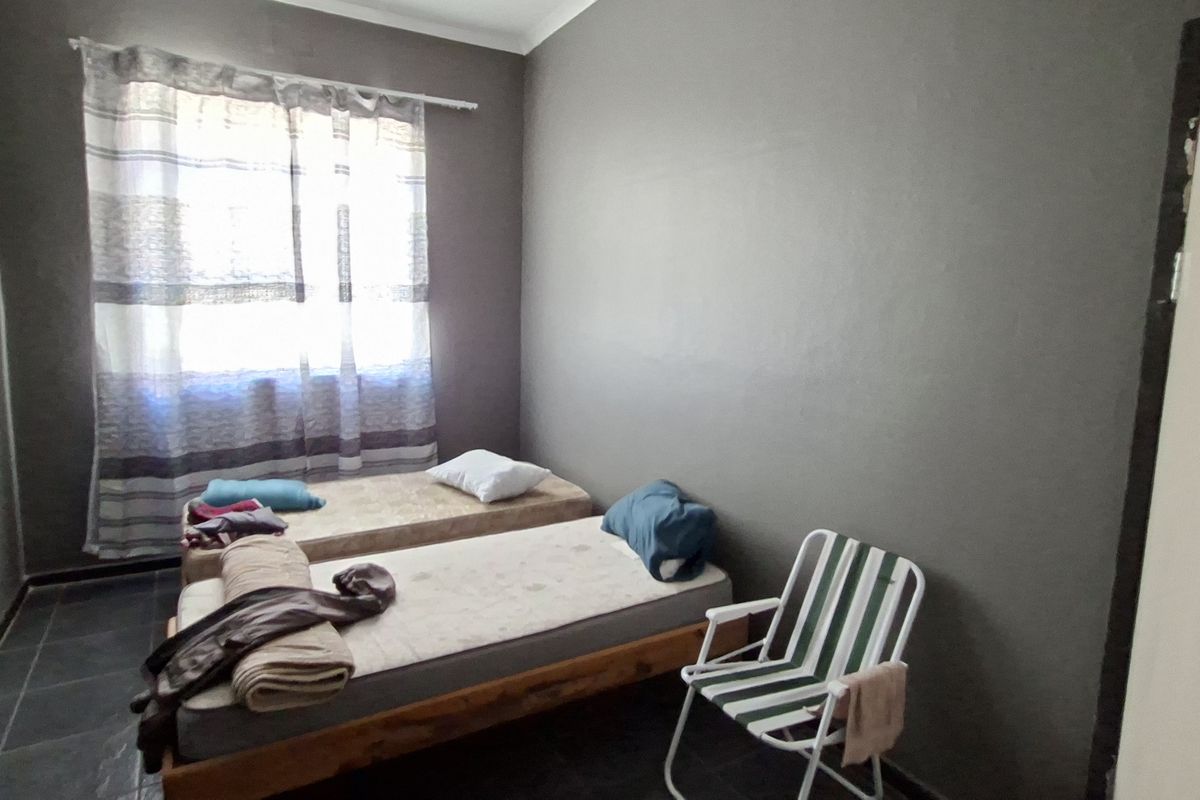 A compact bedroom featuring dark tiled flooring and neutral wall finishes, offering a functional space ready for modernization and personal styling.