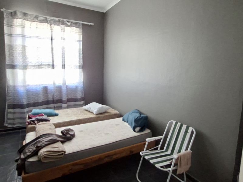 A compact bedroom featuring dark tiled flooring and neutral wall finishes, offering a functional space ready for modernization and personal styling.