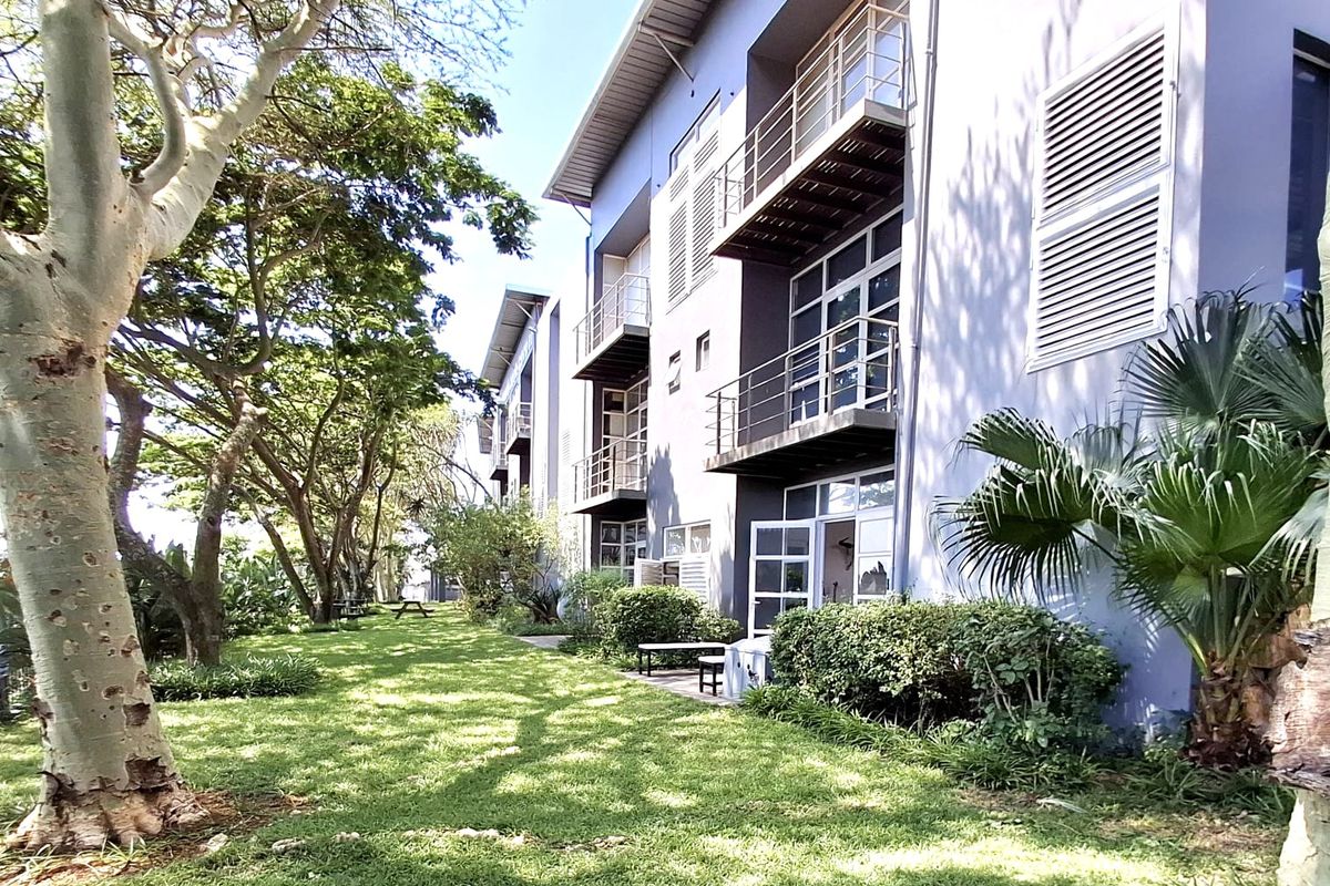 Rear exterior view of the office building featuring multiple balconies, metal railings, and well-maintained landscaped garden areas.