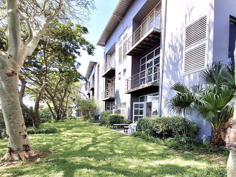 Rear exterior view of the office building featuring multiple balconies, metal railings, and well-maintained landscaped garden areas.