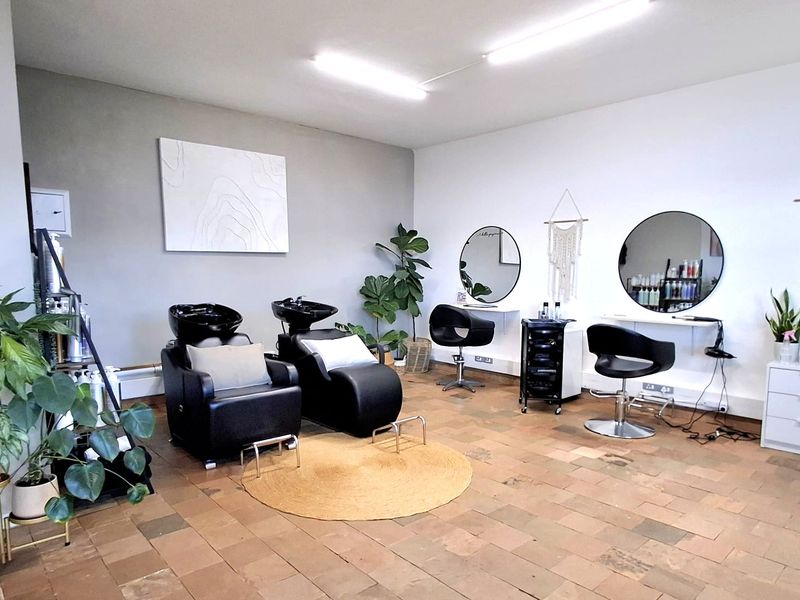 A well-maintained commercial office space currently utilized as a salon, featuring durable tiled flooring and functional overhead lighting.