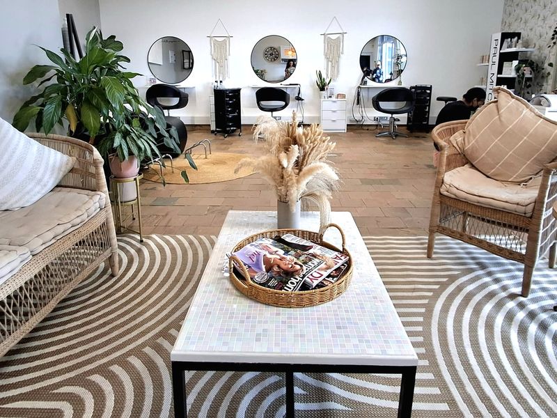 A well-lit salon or office space featuring multiple wall-mounted styling stations with circular mirrors and durable tiled flooring.
