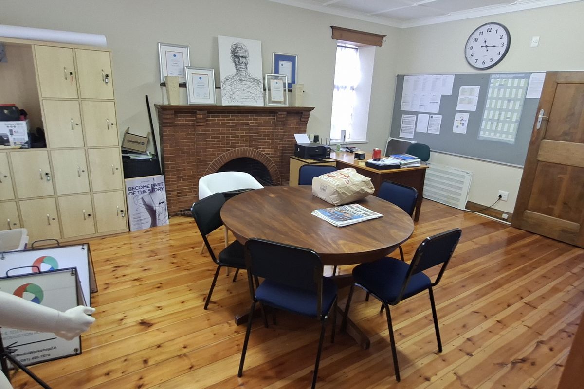 A functional office space featuring polished wooden flooring, a classic brick fireplace, and built-in storage lockers, providing a practical work environment.
