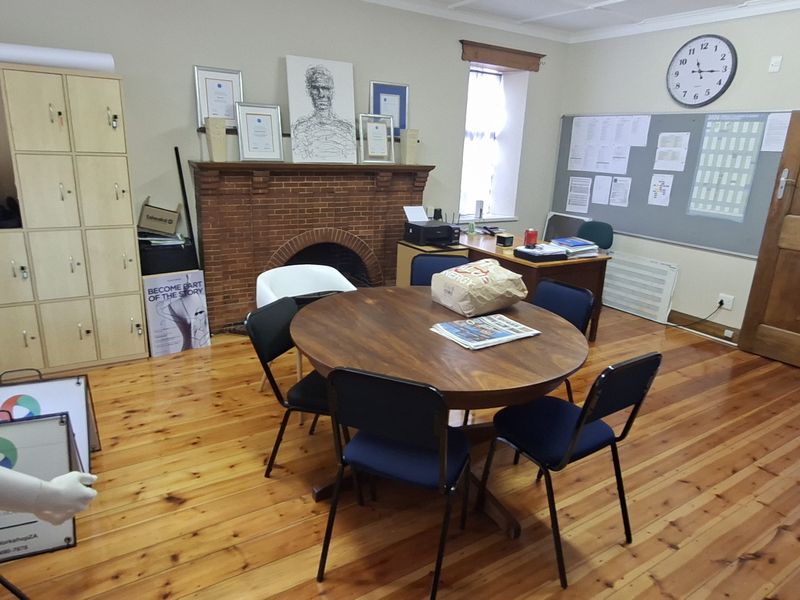 A functional office space featuring polished wooden flooring, a classic brick fireplace, and built-in storage lockers, providing a practical work environment.