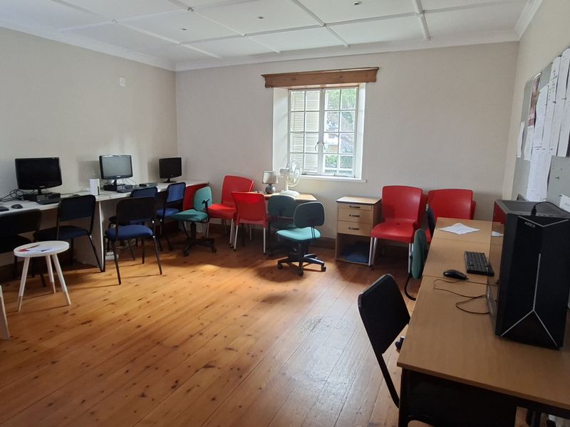 A functional office space featuring timber flooring, a suspended ceiling, and built-in desk areas, suitable for a collaborative work environment.