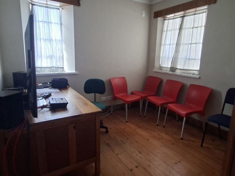 A functional office space featuring timber flooring and dual windows, providing a practical layout for a professional work environment.