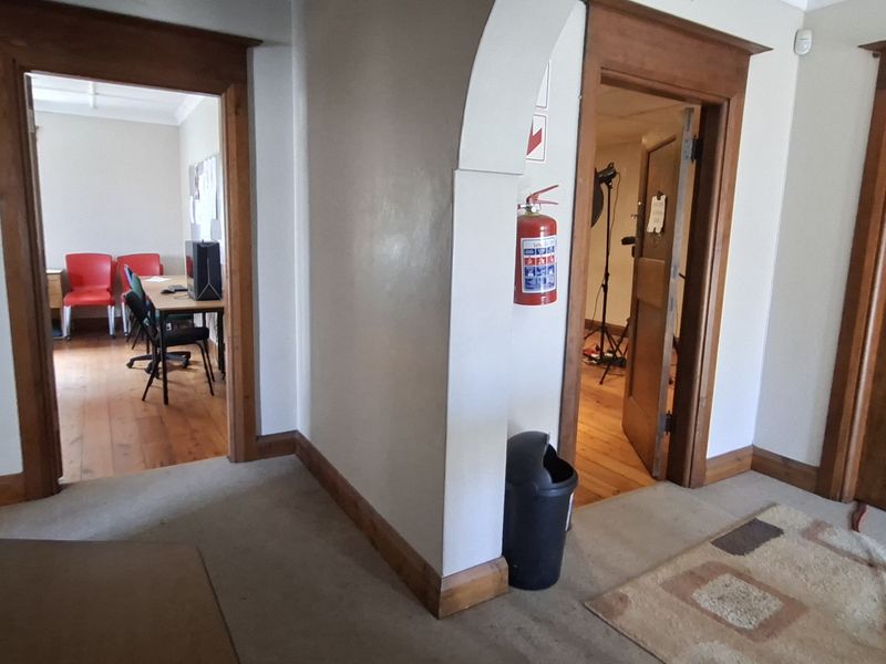 A functional office hallway featuring wooden door frames, an arched transition, and access to multiple office rooms.