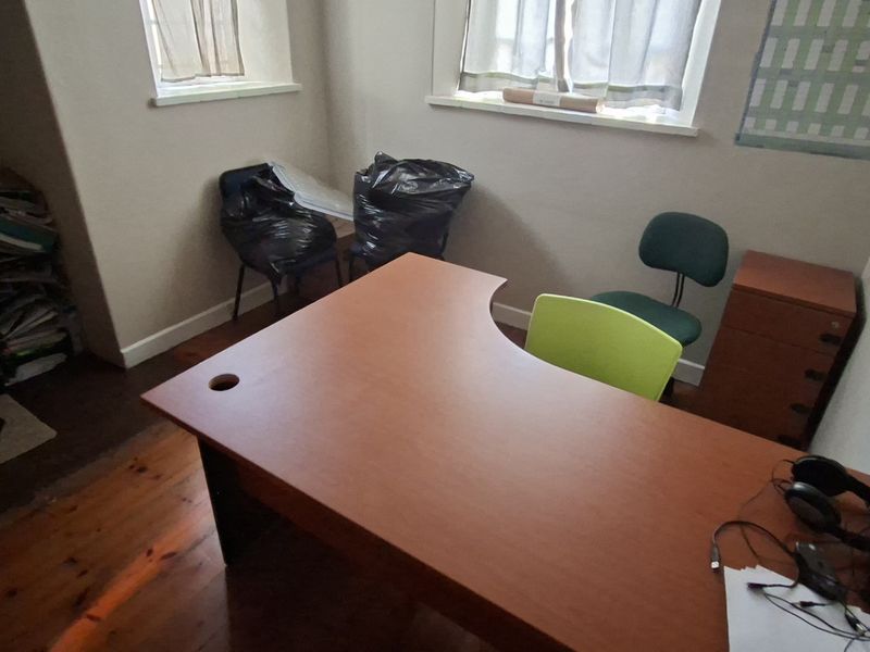 A compact office space featuring polished timber flooring and two windows, providing a functional workspace environment.