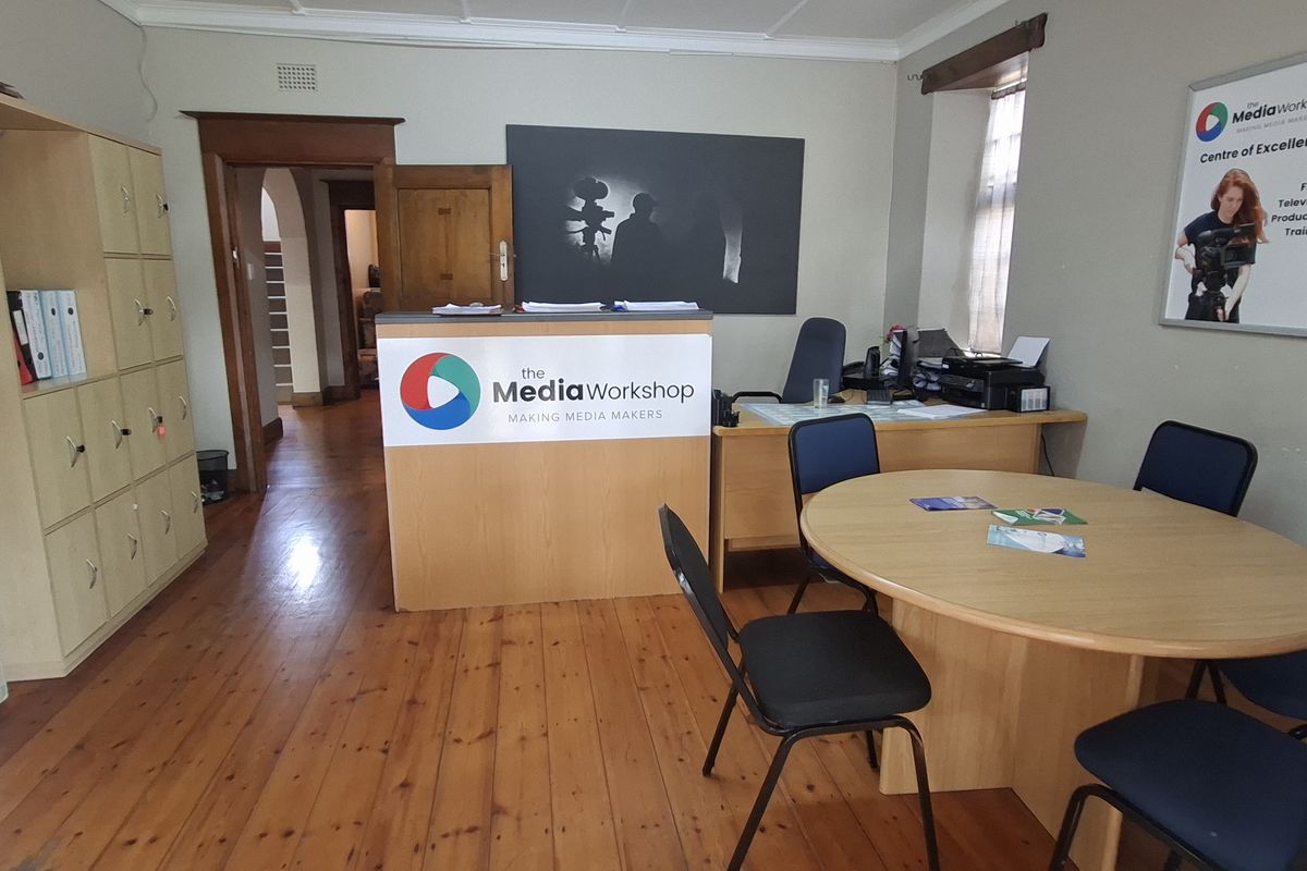 A functional office space featuring polished timber flooring, built-in storage cabinetry, and a central reception desk, suitable for professional use.