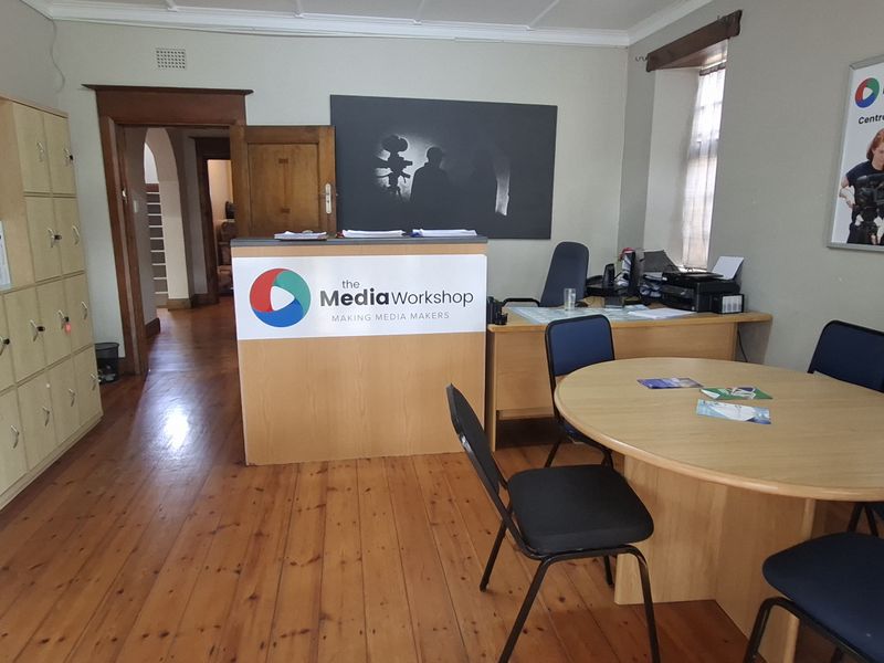 A functional office space featuring polished timber flooring, built-in storage cabinetry, and a central reception desk, suitable for professional use.