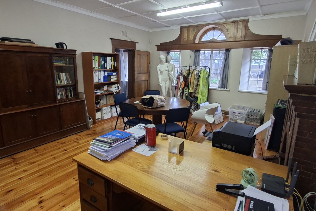 Spacious office featuring polished hardwood flooring, built-in wooden cabinetry, and a classic brick fireplace surround with arched window detailing.