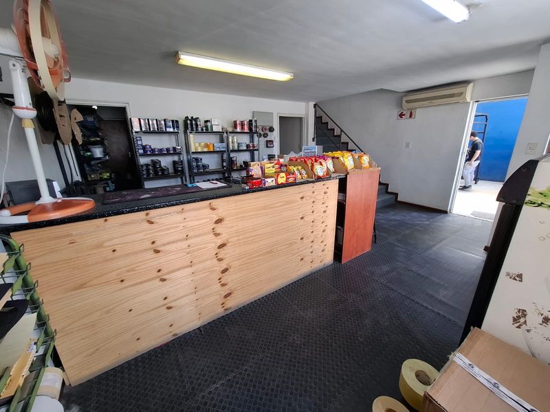 Industrial utility space featuring a built-in service counter, staircase access, air conditioning, and durable rubber flooring, suitable for retail or operational use.