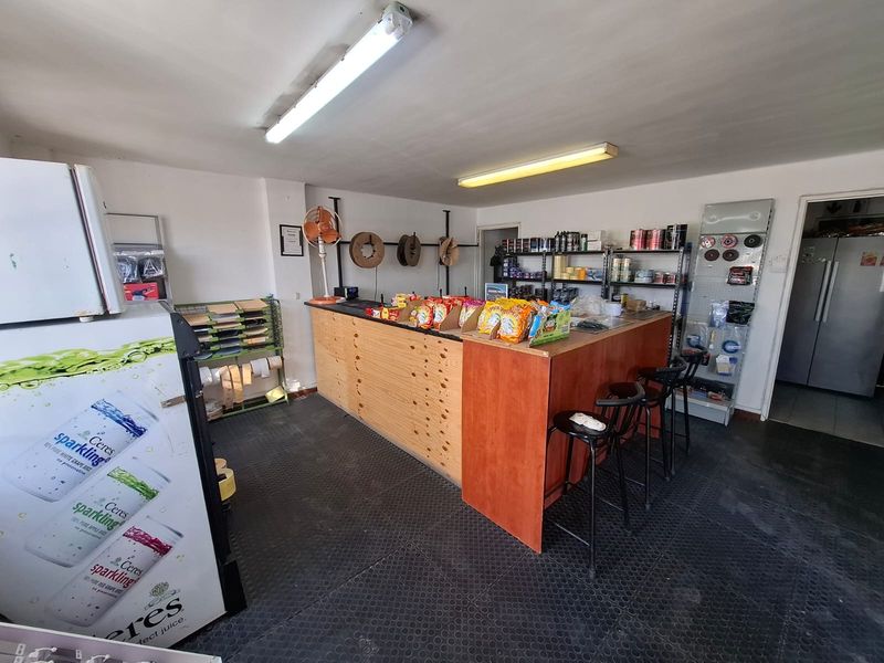 A functional industrial utility or service space featuring a built-in counter, durable rubber flooring, and integrated metal shelving for storage and display.