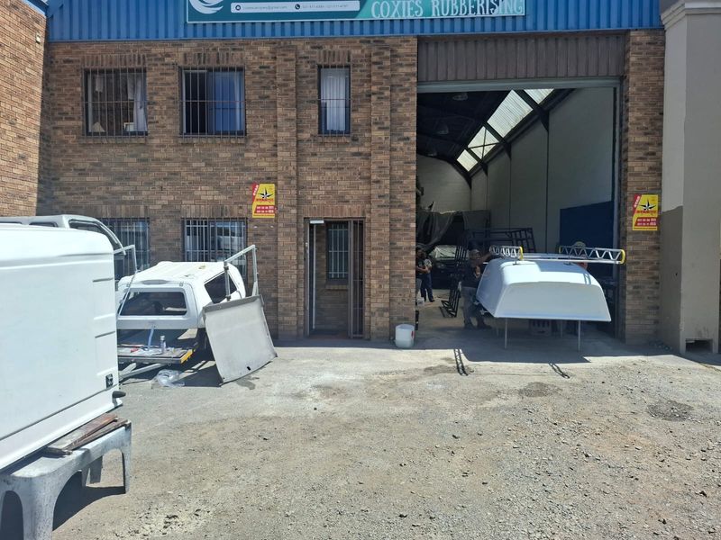 Front elevation of an industrial workshop featuring a brick facade, security-barred windows, and a large roller door entrance.