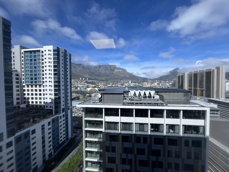 Elevated urban view overlooking surrounding high-rise office buildings and the mountain range in the distance.