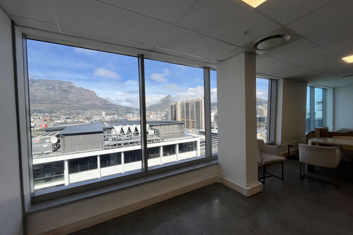 Modern office space featuring polished concrete floors, suspended ceilings, and expansive floor-to-ceiling windows offering panoramic mountain and city views.