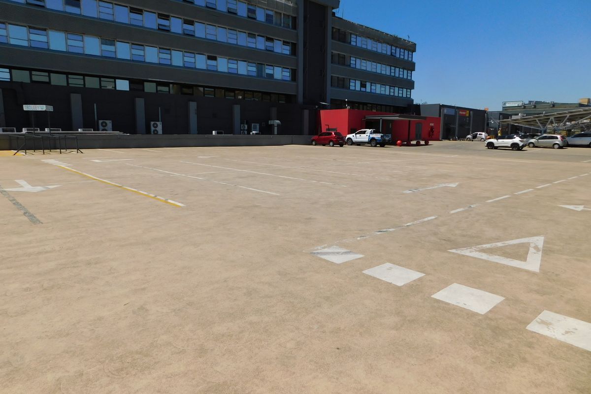 A large paved outdoor parking area adjacent to a multi-story office building with clearly marked parking bays.