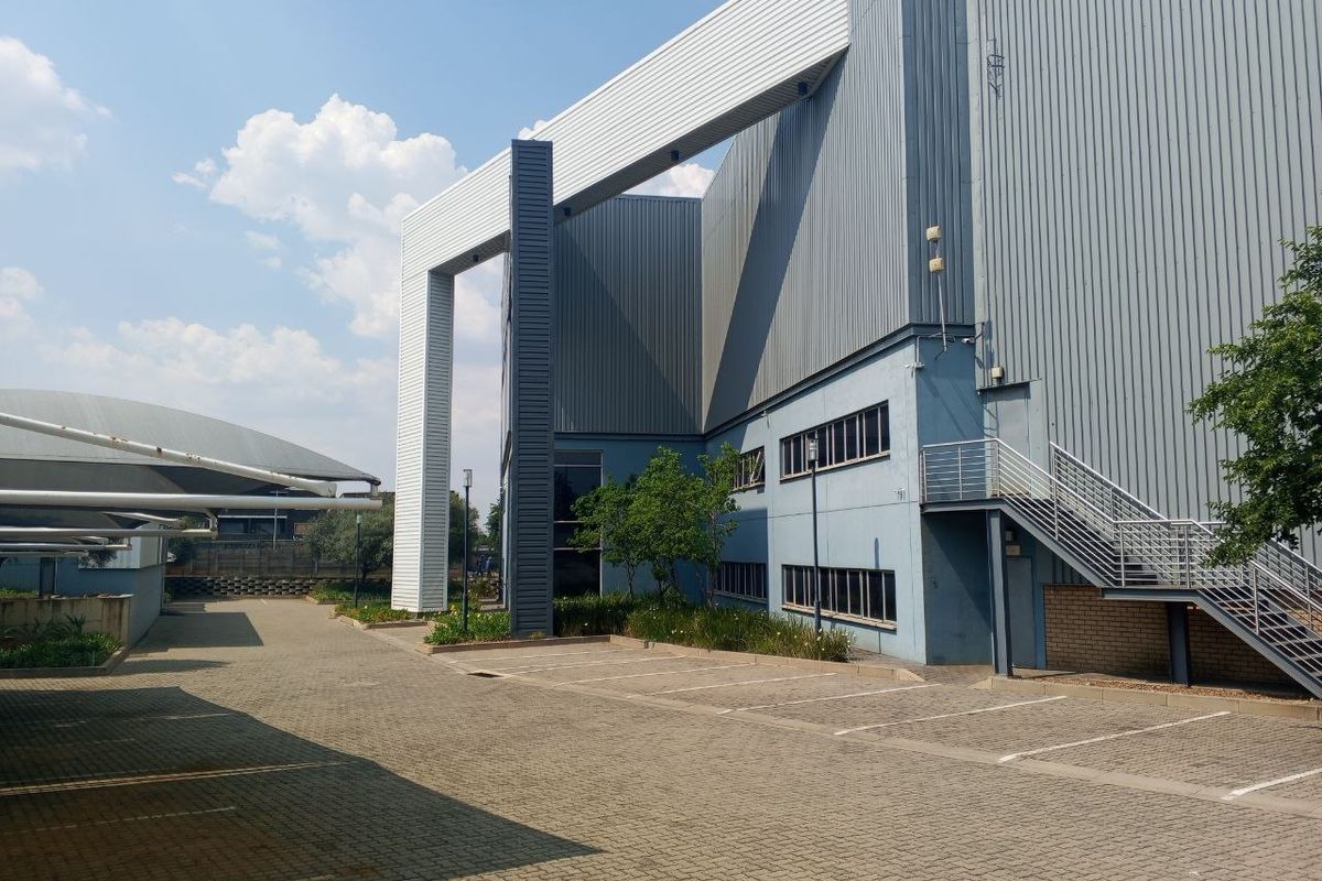 Exterior view of an industrial property featuring corrugated metal cladding, a paved parking area, and an external steel staircase.