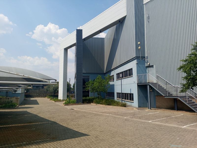 Exterior view of an industrial property featuring corrugated metal cladding, a paved parking area, and an external steel staircase.
