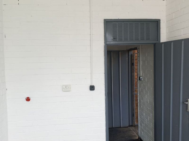 A functional utility space featuring painted brick walls, industrial-style door, and surface-mounted electrical infrastructure.