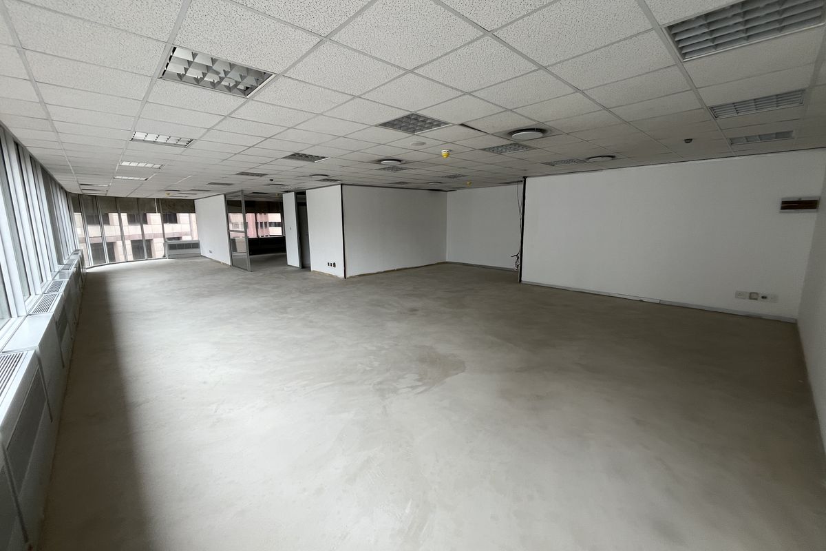 A spacious, open-plan office area featuring a suspended ceiling, recessed lighting, and large windows providing ample natural light.