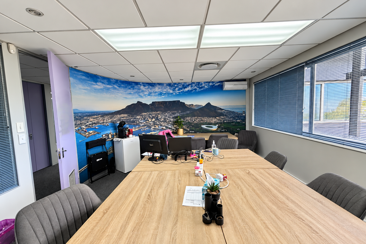 A functional office space featuring a suspended ceiling, recessed lighting, air conditioning, and large windows with venetian blinds, suitable for professional use.