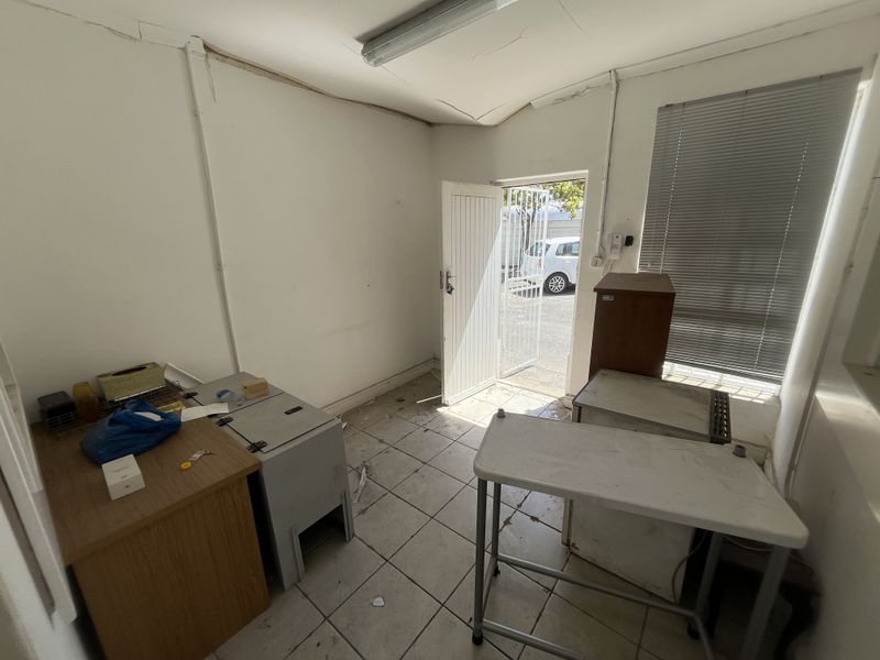 A functional utility space featuring tiled flooring, a security gate, and natural light, currently requiring maintenance and cosmetic updates.