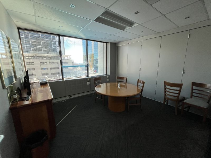 A functional office space featuring a suspended ceiling, recessed lighting, and large windows providing natural light and city views.