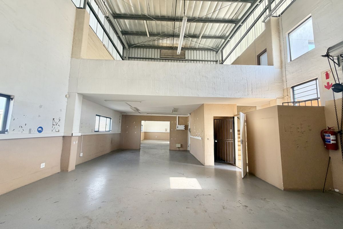 Spacious industrial utility area featuring a mezzanine level, high ceilings with exposed steel structure, and durable concrete flooring, suitable for various commercial or storage uses.