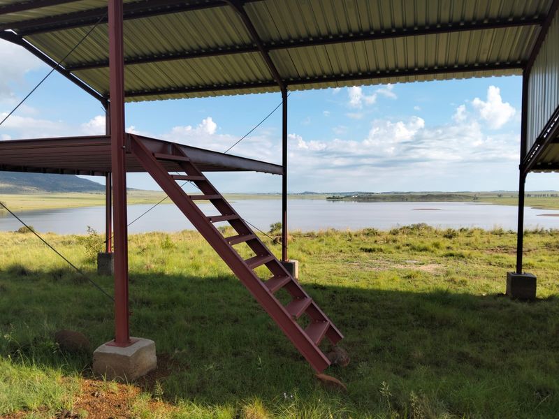 An open-air steel structure with a raised platform and staircase, offering expansive views over the surrounding landscape and water.