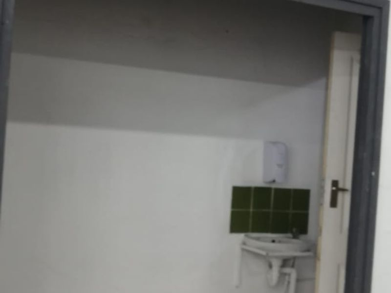 A small utility area featuring a wall-mounted basin with a tiled splashback and tiled flooring, suitable for a wash-up or prep station.