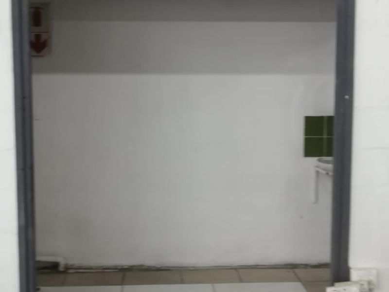 A functional utility space featuring tiled flooring, a wall-mounted basin with splashback, and existing electrical infrastructure, suitable for storage or service use.