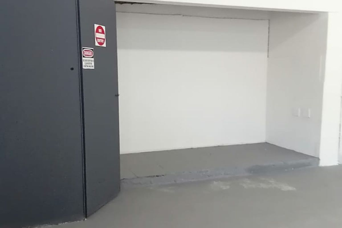 An empty utility or storage space featuring painted concrete flooring and exposed ceiling structure, suitable for various commercial storage or operational uses.