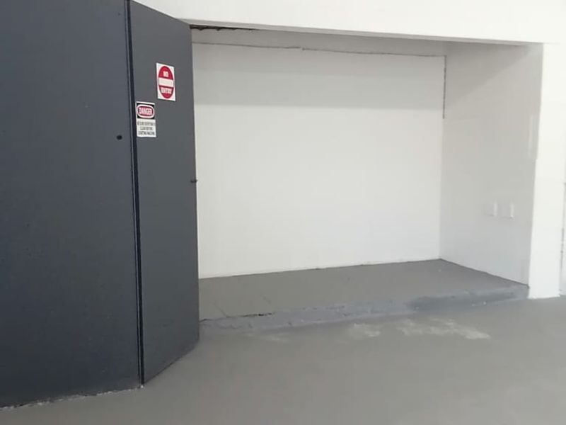 An empty utility or storage space featuring painted concrete flooring and exposed ceiling structure, suitable for various commercial storage or operational uses.