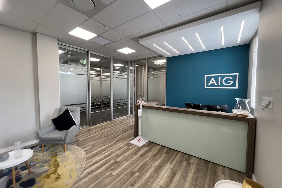 Modern office reception area featuring a professional desk, glass partition walls, and contemporary lighting in a well-maintained corporate environment.