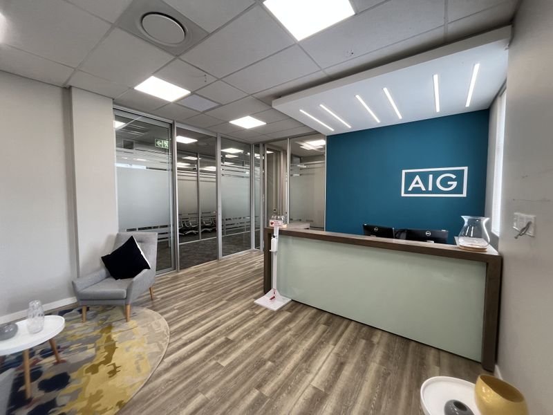 Modern office reception area featuring a professional desk, glass partition walls, and contemporary lighting in a well-maintained corporate environment.