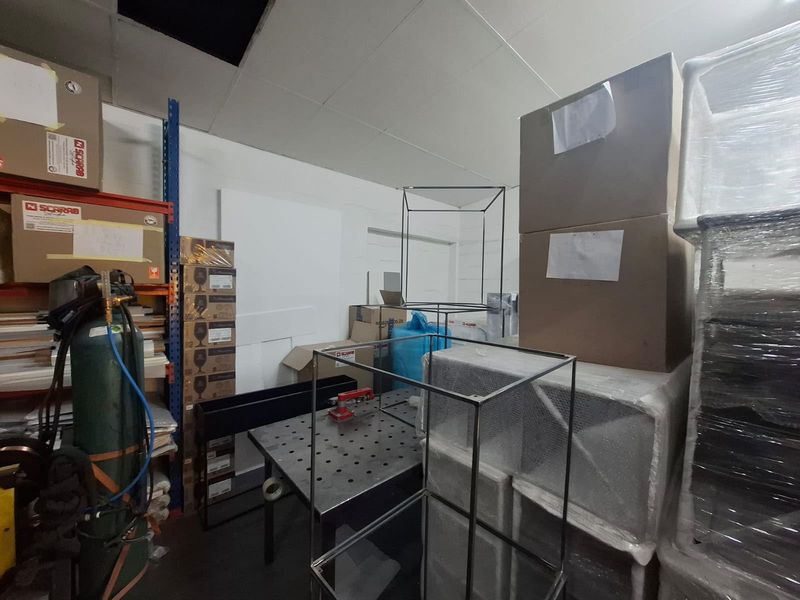 Industrial utility space featuring heavy-duty shelving units and a suspended ceiling system, currently utilized for storage and workspace operations.