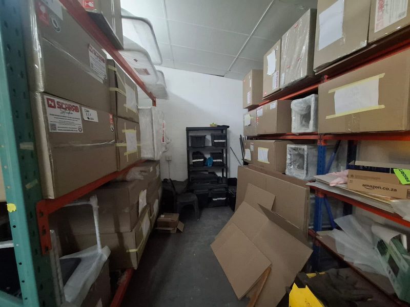 A functional industrial utility or storage space featuring heavy-duty metal shelving units and concrete flooring, currently utilized for inventory storage.