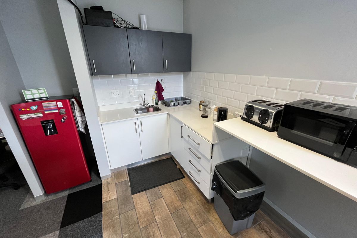 Compact office kitchenette featuring white cabinetry, subway tile backsplash, stone-look countertops, and a stainless steel sink.