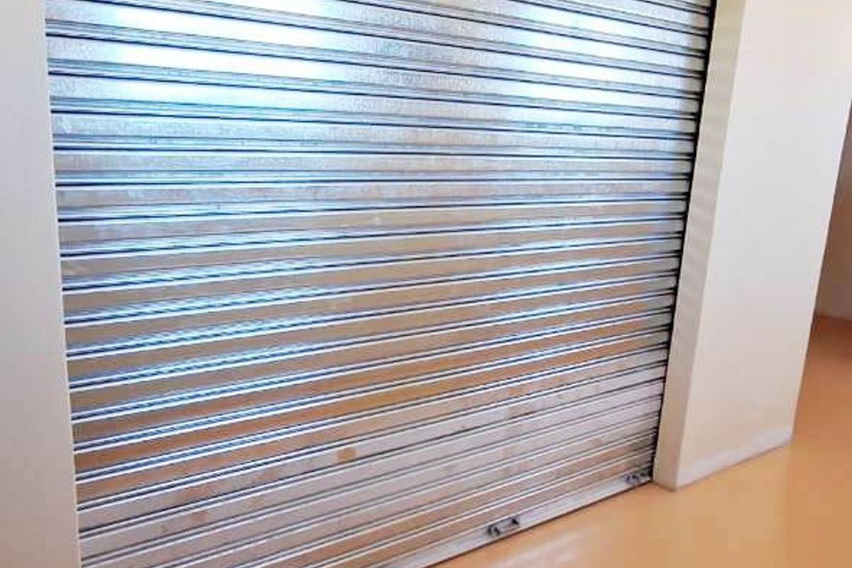 A clean interior space featuring a secure metal roller shutter door and smooth flooring, suitable for retail storage or utility use.