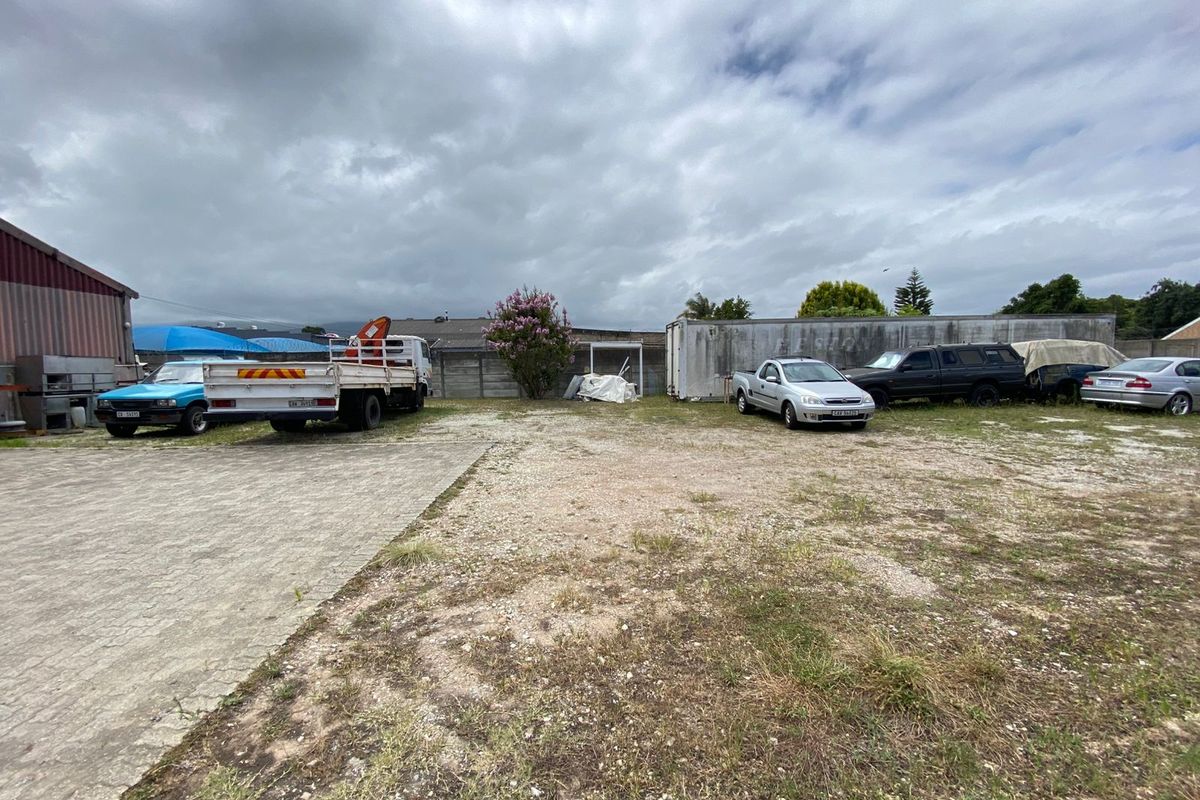 Expansive industrial yard area featuring paved sections, gravel surfaces, and perimeter boundary walling, suitable for storage or vehicle parking.