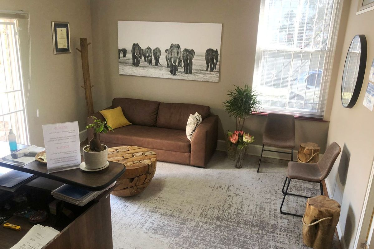 A professional office reception area featuring a wall-mounted air conditioning unit, large window with blinds, and neutral wall finishes.