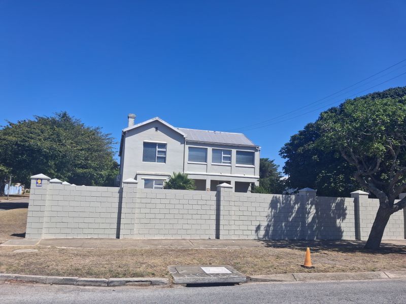 A view of the property exterior featuring a solid perimeter boundary wall and a two-story building structure.