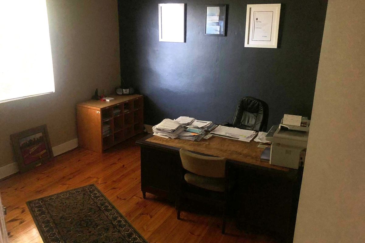 A functional office space featuring polished timber flooring and a dark accent wall, providing a professional environment for work.