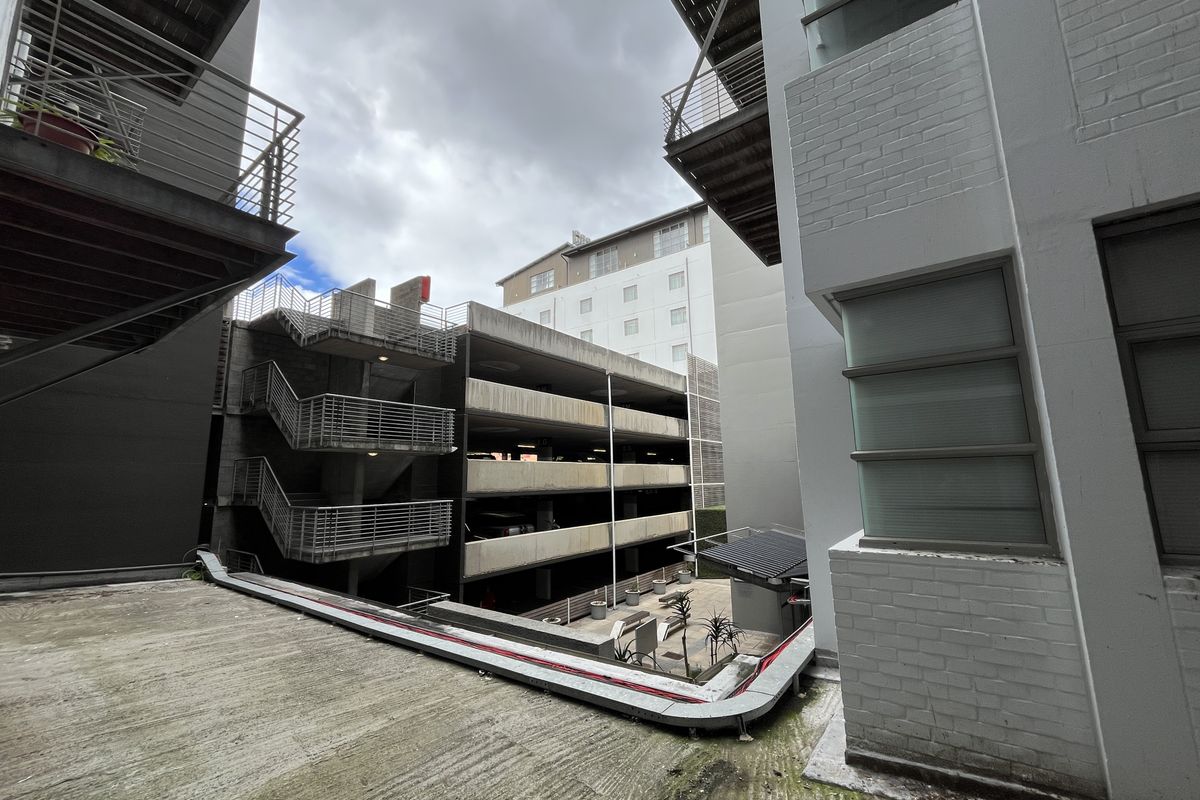 Exterior view of the office complex showing multi-level parking structure, metal staircases, and concrete walkways between building blocks.