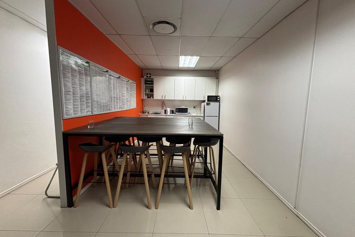 A functional office kitchenette area featuring white cabinetry, tiled flooring, and a suspended ceiling with integrated lighting.