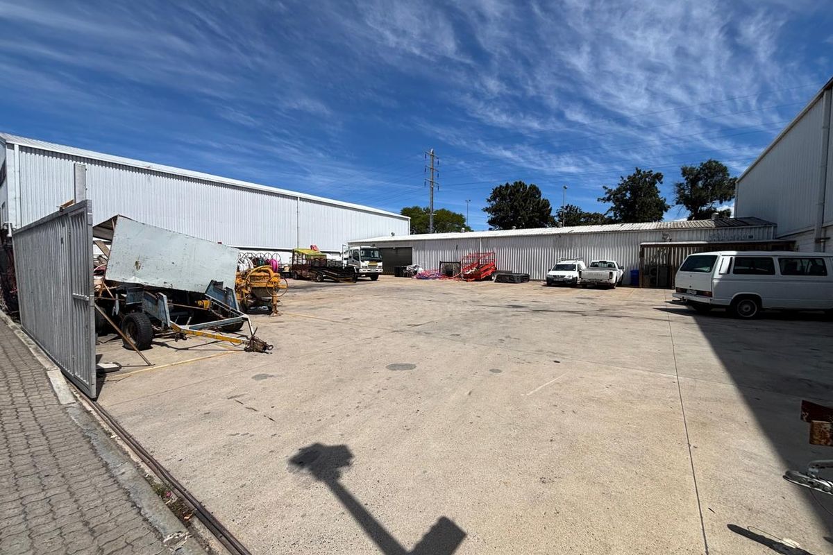 Spacious industrial yard area featuring concrete hardstand, metal cladding warehouse structures, and secure gated access.