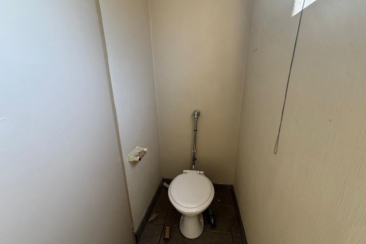A small, functional restroom featuring a standard toilet and tiled flooring, requiring minor cosmetic updates.