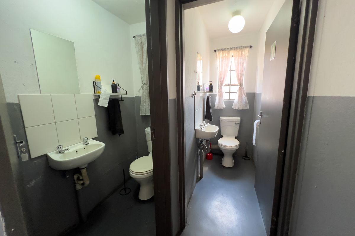 Two adjacent office restrooms featuring wall-mounted basins, toilets, and simple tiled splashbacks with a functional, utilitarian design.
